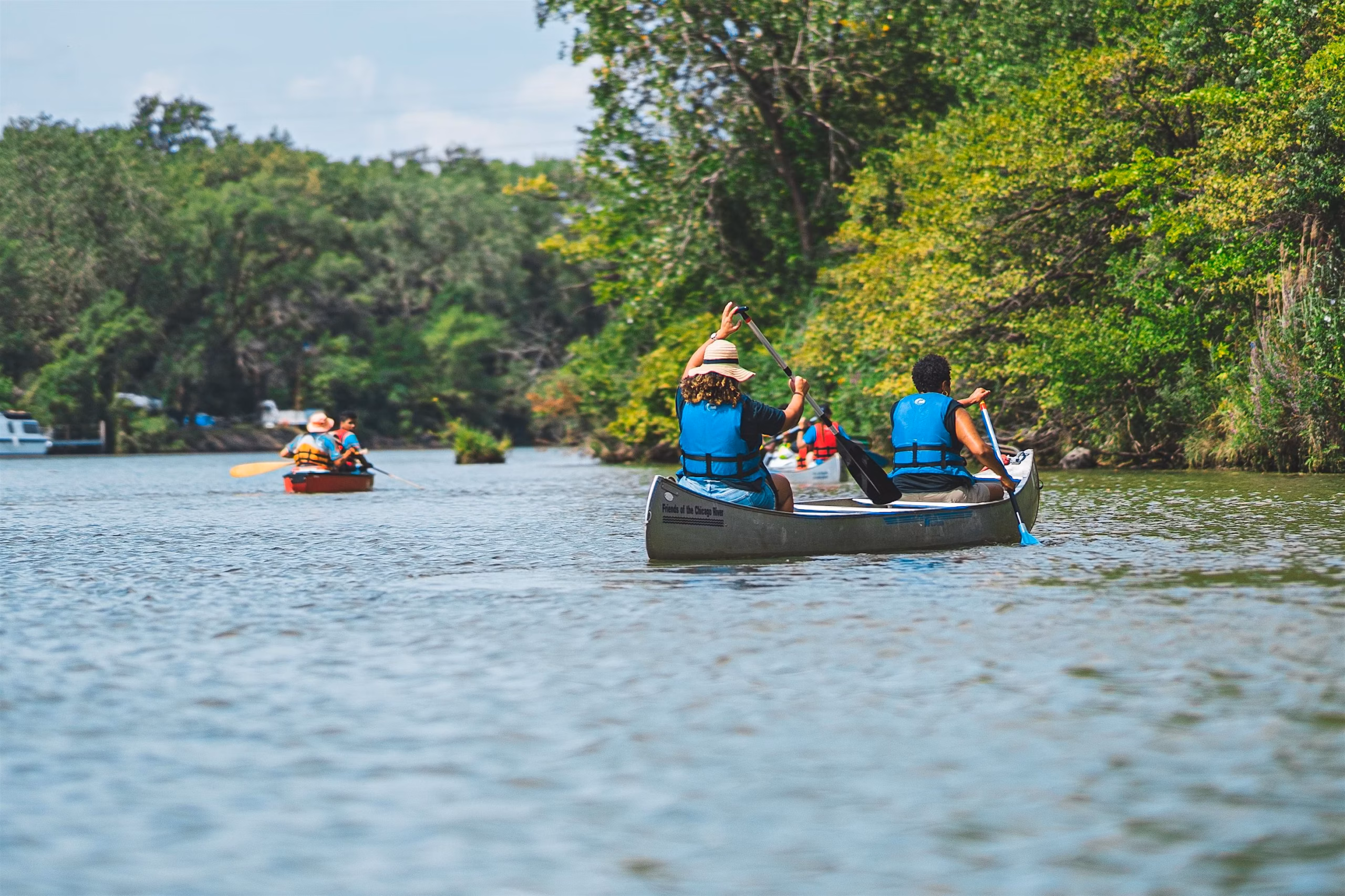 three canoes with blue vest travelers paddling across a river