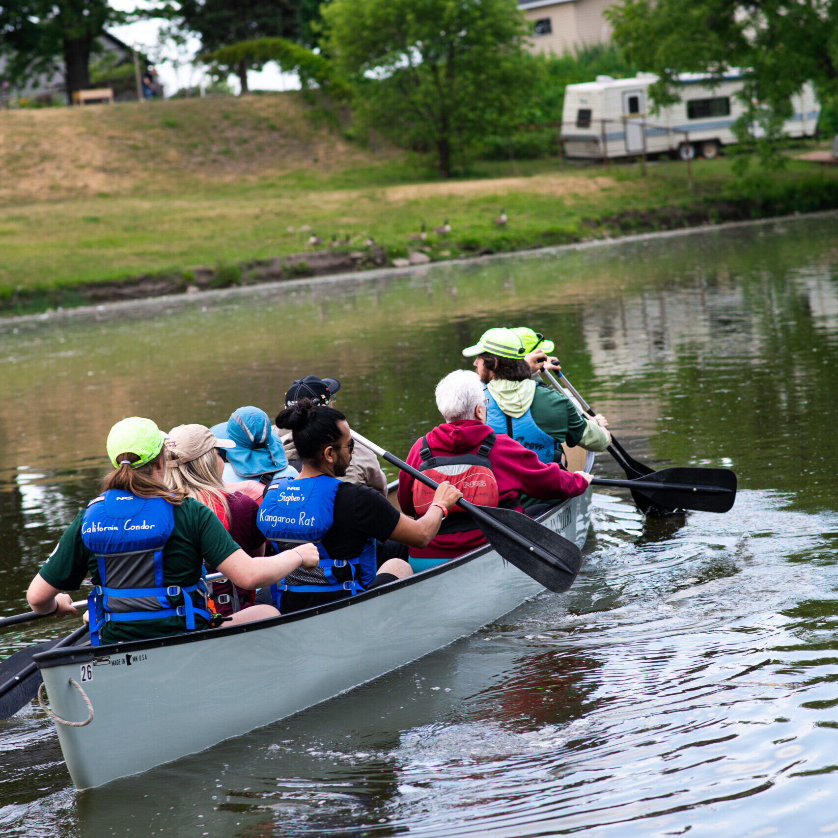 A group of people paddling together in a canoe on calm water, enjoying a day outdoors.