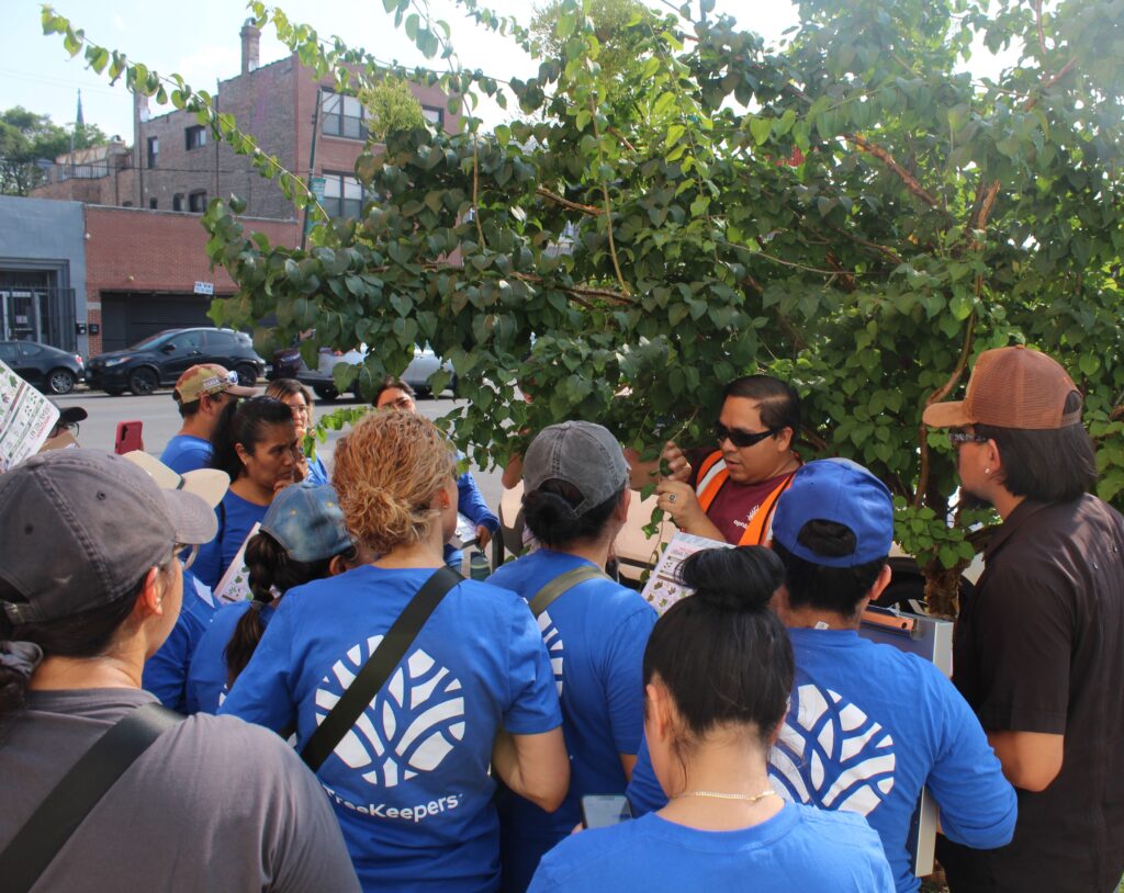 An instructor teaching his students about forestry in front of a tree.