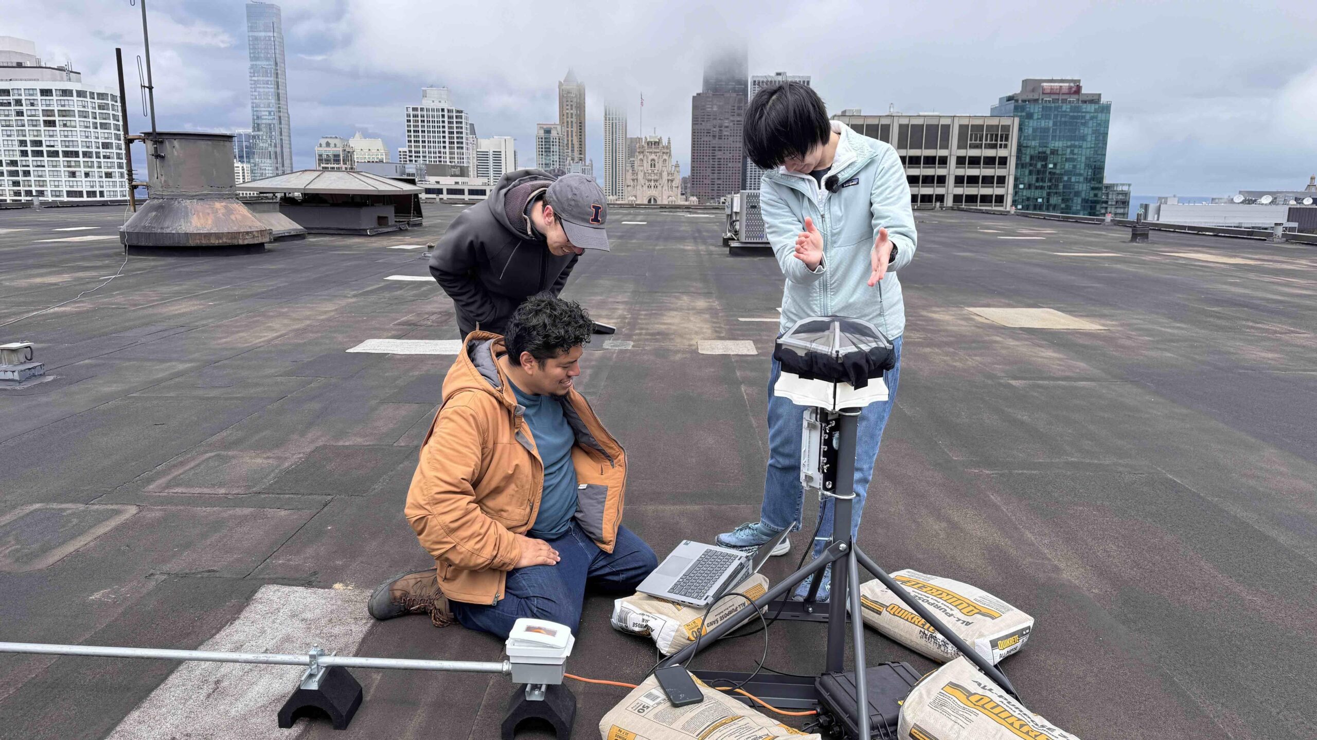 Three people on top of roof installing acoustic monitoring device to track bird migration.