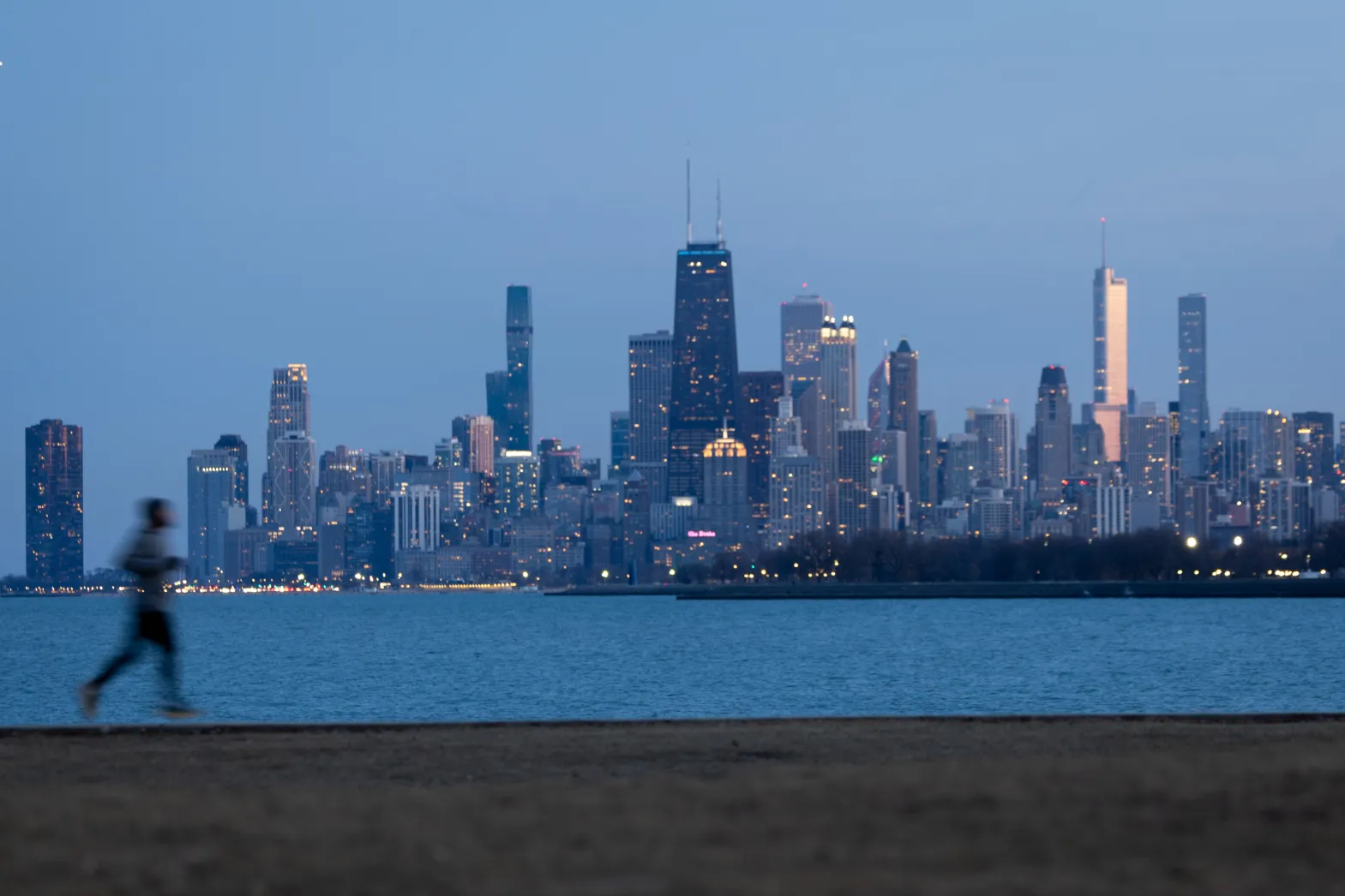 Jogger running along edge of Lake Michigan with Chicago Skyline in background